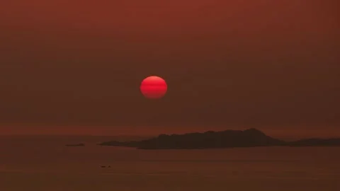 Orange sky with sun going down into sea Видео 221398690