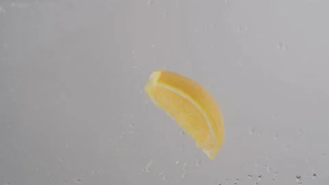 Orange slice dropping into water in slow motion 库存影片 220755813