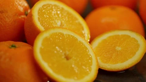 An orange slice effectively falls on a wet surface and creates splashes. Stock Footage 276173398