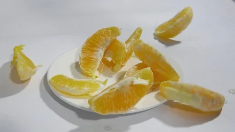 Orange slices fall on a white plate in slow motion 스톡 동영상 105646351