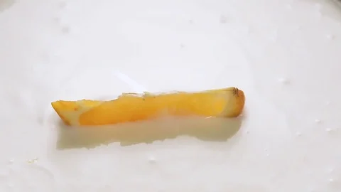 Orange slices falling into yogurt with splashes, slow motion. Stock Footage 84953567