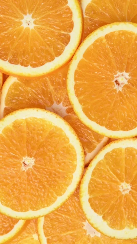 Orange slices rotate in a vertical frame, creating a vivid citrus pattern with Stock Footage 346673301