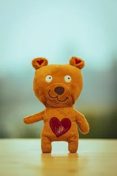 Orange small teddy bear with a red heart-shaped patch on its chest, indicating l Foto stock