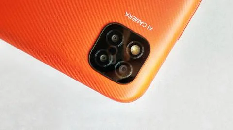 Orange smartphone with Artificial Intelligence (AI) cameras. Stock Photos