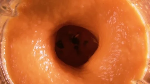 Orange smoothie is blending in blender with splashes, top view, slow motion. Stock Footage 127157629