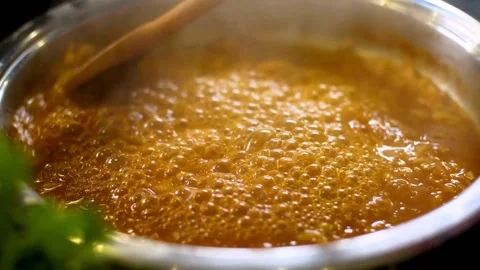 Orange soup boiling in pot stirred with wooden spoon Stock Footage 333835529
