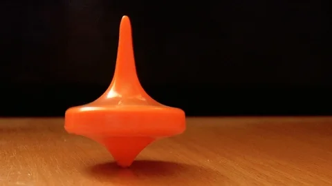Orange spinning top spinning on the table Stock Footage 86378727