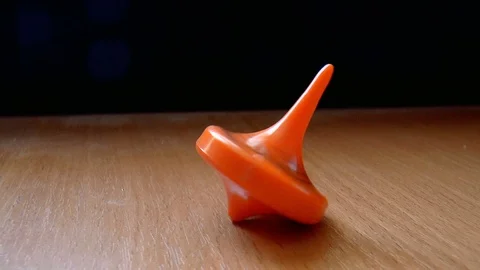 Orange spinning top spinning on the table Stock Footage 86378931