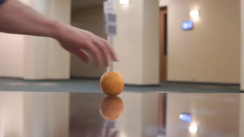 The orange spins on the glass surface of the table, then stops. Vídeos de archivo 103677125