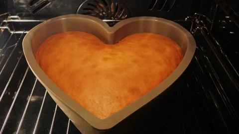 Orange sponge cake heart shaped baked in the oven. Valentines day. Time lapse. Stock Footage 259396041