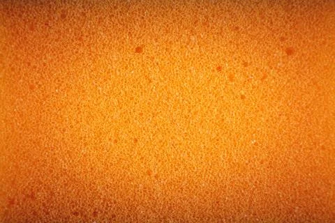 Orange sponge made of microfiber material. Texture, background. In Increase Фото