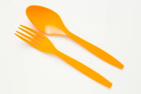 Orange spoon and fork on white canvas background Stock Photos