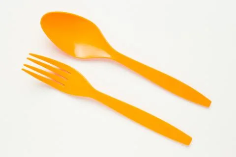 Orange spoon and fork on white canvas background Stock Photos