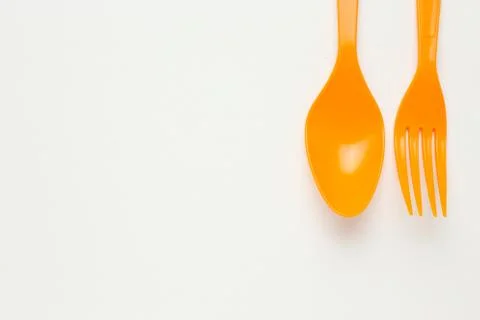 Orange spoon and fork on white canvas background Stock Photos