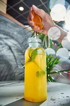 The orange is squeezed into a bottle of fresh lemonade. Close-up, selective f Stock Photos