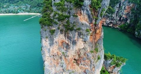 Orange streaked cliff face over a sheltered emerald bay 库存影片 71302276