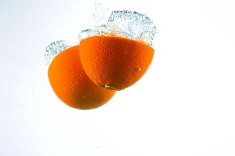Orange in streams of water on a white background Stock Photos