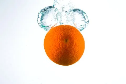 Orange in streams of water on a white background Stock Photos
