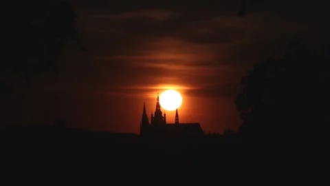 Orange sun glows behind darkened Prague Castle spires 库存影片 335694595