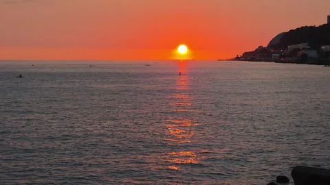 Orange sun at the ocean horizon, casting a bright path across gently rippling 库存影片 348634402