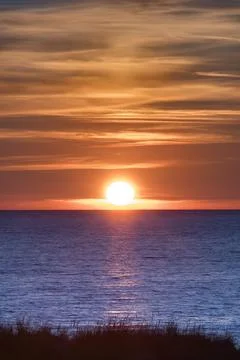 Orange Sun set over blue ocean at Tylosand Beach in Halmstad, Sweden Stock Photos
