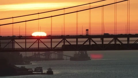 Orange sun sets over the road bridge and a train riding on the second floor of Stock Footage 225166694
