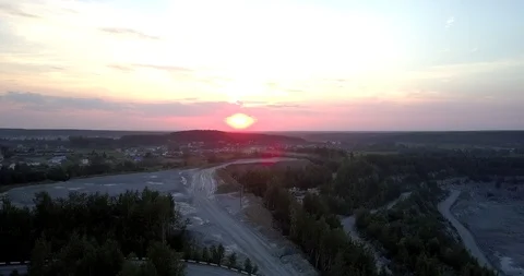 Orange sun sets over small town at outdated mining sector Stockbeeldmateriaal 114427907