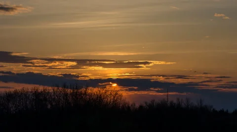 Orange sun setting behind clouds and trees Video stock 68820227