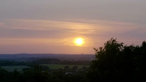 Orange sun setting over a distant city Stock Footage 133464621