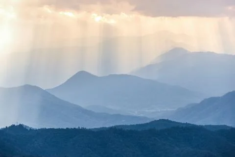 Orange sunbeam from cloudy sky to blue mountains range Foto stock