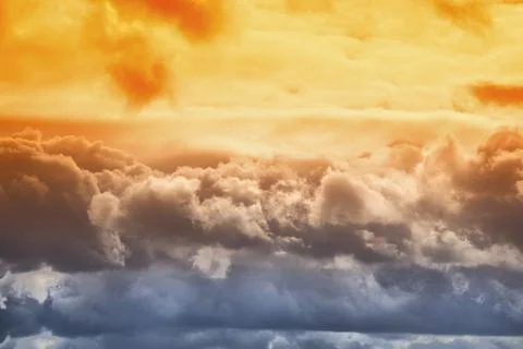 Orange sunlight on clouds in the sky, multicolored blue-orange clouds close-u Stock Photos
