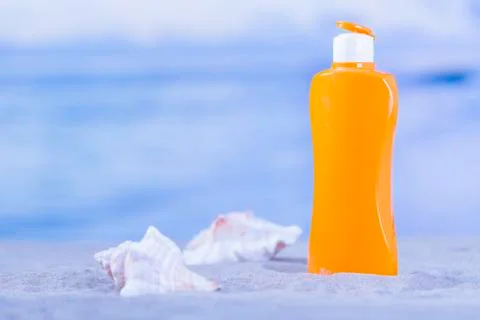 Orange sunscreen bottle with a pair of seashells Stock Photos