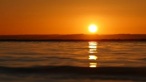An orange sunset with a close up of water Stock Footage 86409146