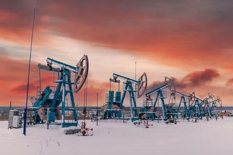 At the orange sunset dawn of the sky with clouds seven Oil pumpjack winter wo Stock Photos