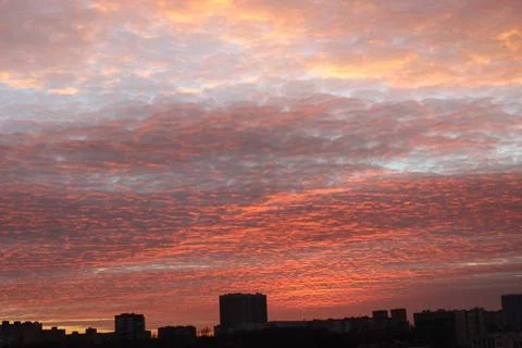 An orange sunset that illuminates the clouds flying by over the already night-ti Stock Photos