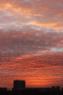 An orange sunset that illuminates the clouds flying by over the already night-ti Stock Photos