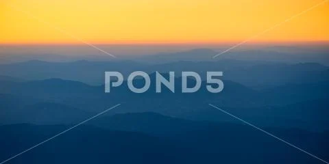 Orange sunset in the mountains. View from a height. Stock Photos