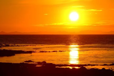 Orange sunset over ocean with reflection on water Stock Photos
