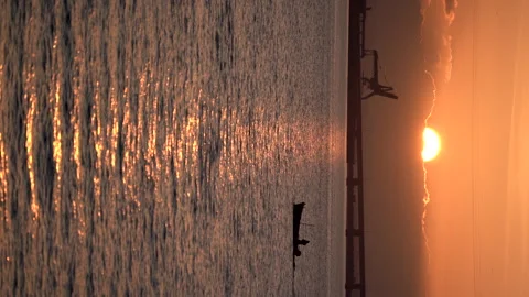 Orange sunset over the ocean with sun in sky and boat floating by the water. Video stock 240189127