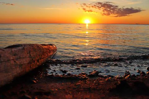 Orange sunset over the river with a log and small wave Stock Photos