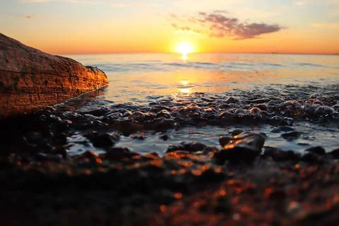 Orange sunset over the river with a log and small wave Stock Photos