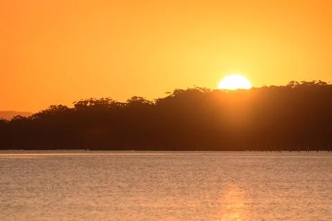 Orange sunset over the trees, view from the bank over the river. Foto stock