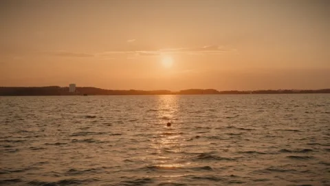 Orange sunset over water with distant coastline and clouds Stock Footage 292868933