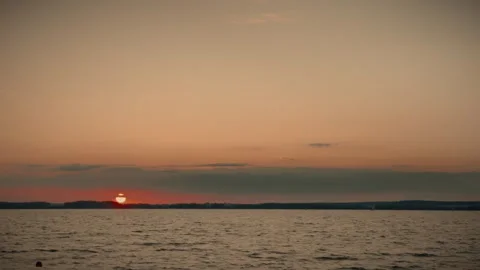 Orange sunset over water with distant coastline and clouds Video stock 292868952
