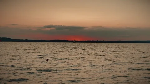 Orange sunset over water with distant coastline and clouds Video stock 292868960