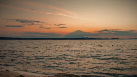 Orange sunset over water with distant coastline and clouds Stock Footage 292868971