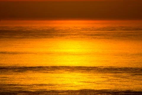 The orange sunset reflected in the small waves. Stock Photos