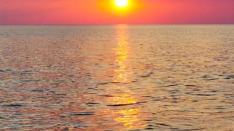 The orange sunset reflected in the small waves. Stock Photos