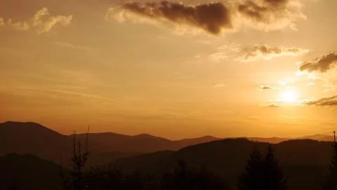Orange sunset with the setting sun behind the mountains Stock Photos