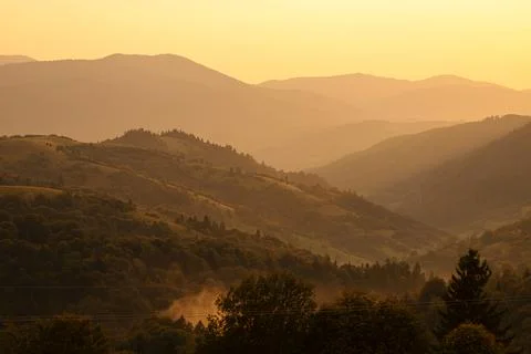 Orange sunset with the setting sun behind the mountains Stock Photos